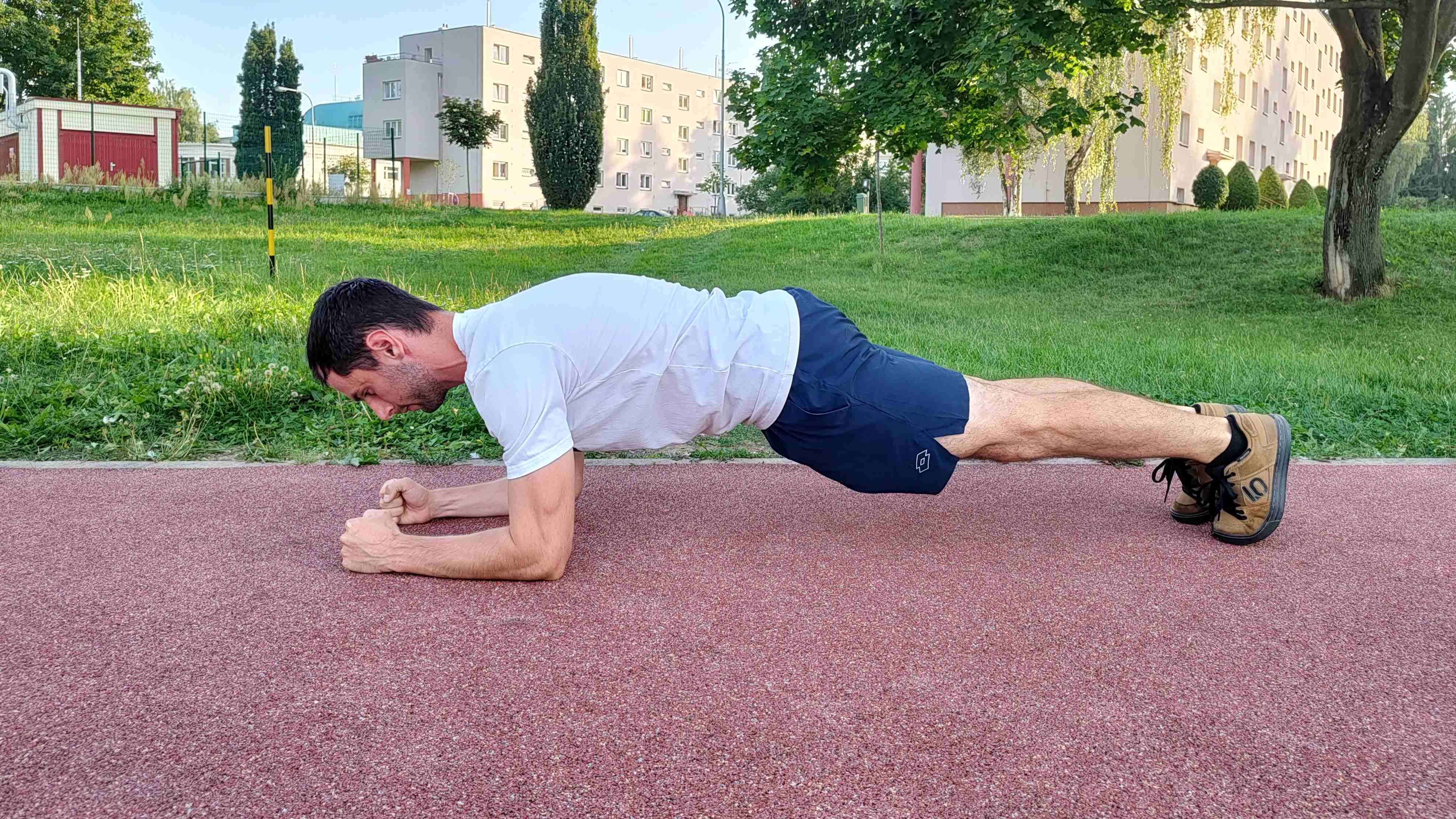 Muž cvičí plank v parku.